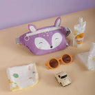 Purple fox-themed pouch with baby items on a beige surface