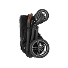 A profile view of a folded black MIXX Next + Pipa Aire RX Travel System by Nuna stroller featuring a compact fold with an exposed brown leatherette handlebar, set against a checkered transparent background.
