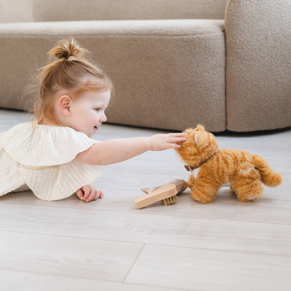 Child playing with a plush toy on a light-colored floor.