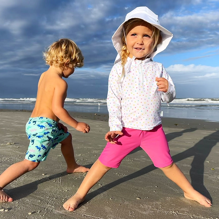 Two children playing on a beach with ocean and sky in the background