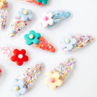 Colorful flower-shaped containers with various colorful contents on a white background