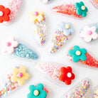Colorful hair clip designs with flowers and confetti on a white background