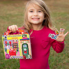 Young girl holding a sticker book and stickers outdoors