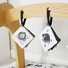 Two small pouches with animal illustrations hanging on a wooden rack.