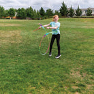 Girl playing with a colorful hula hoop in a grassy field