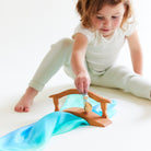 Child playing with a toy mermaid on a white surface