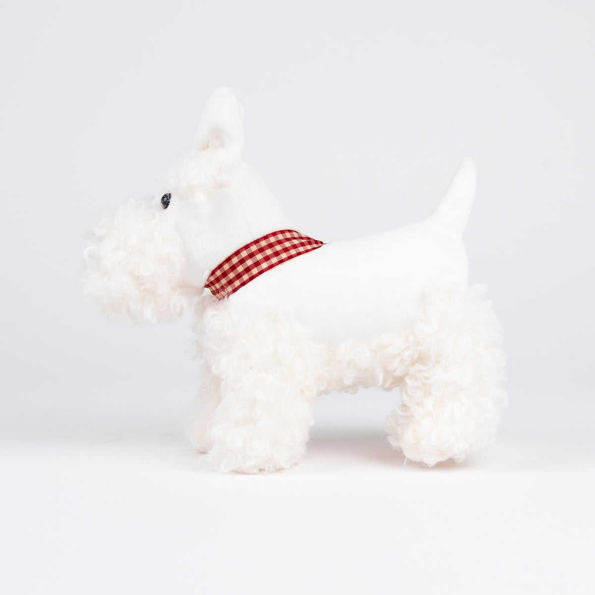 White dog toy with a red checkered ribbon on a white background