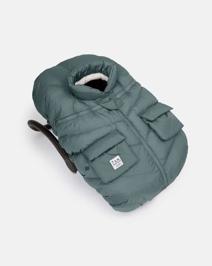 Green baby carrier with a white label on a light gray background