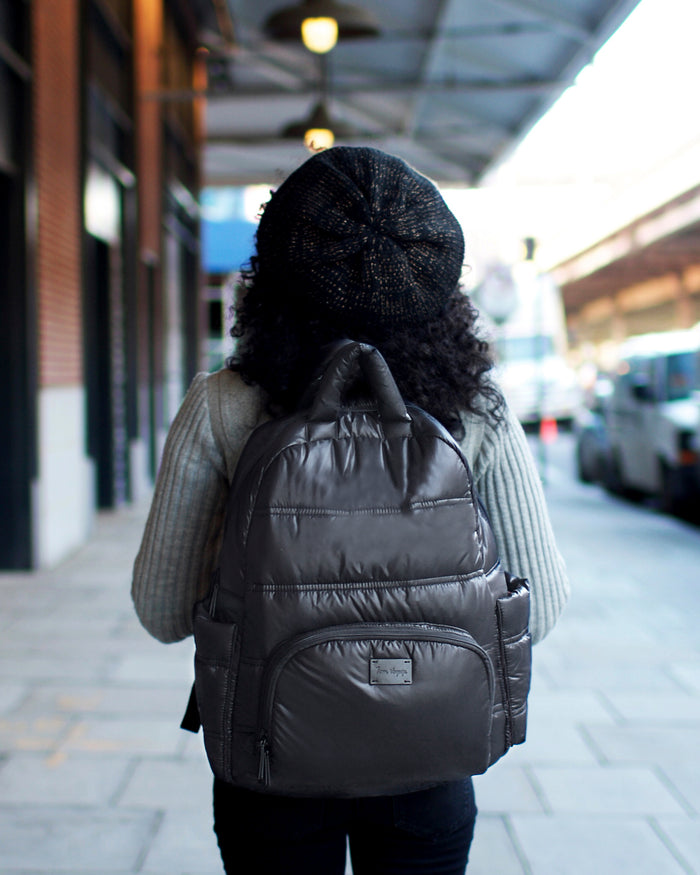 Person wearing a black backpack walking on a city street