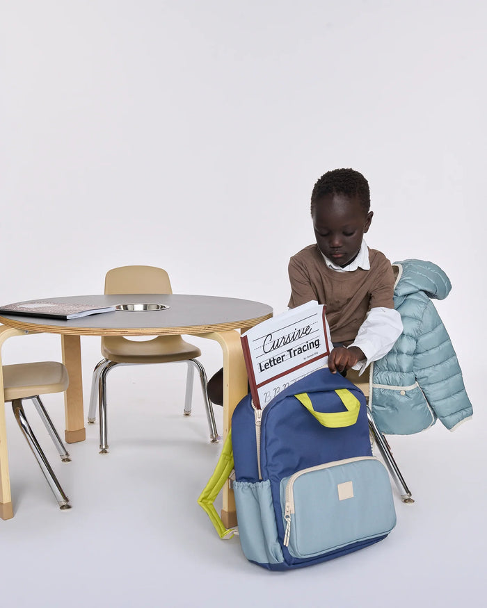Child opening a blue backpack with a white background
