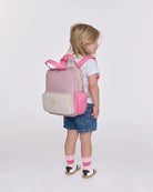 Child wearing a pink and beige backpack on a white background