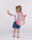 Child wearing a pink and beige backpack on a white background