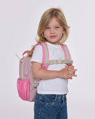 Child wearing a pink and beige backpack on a white background