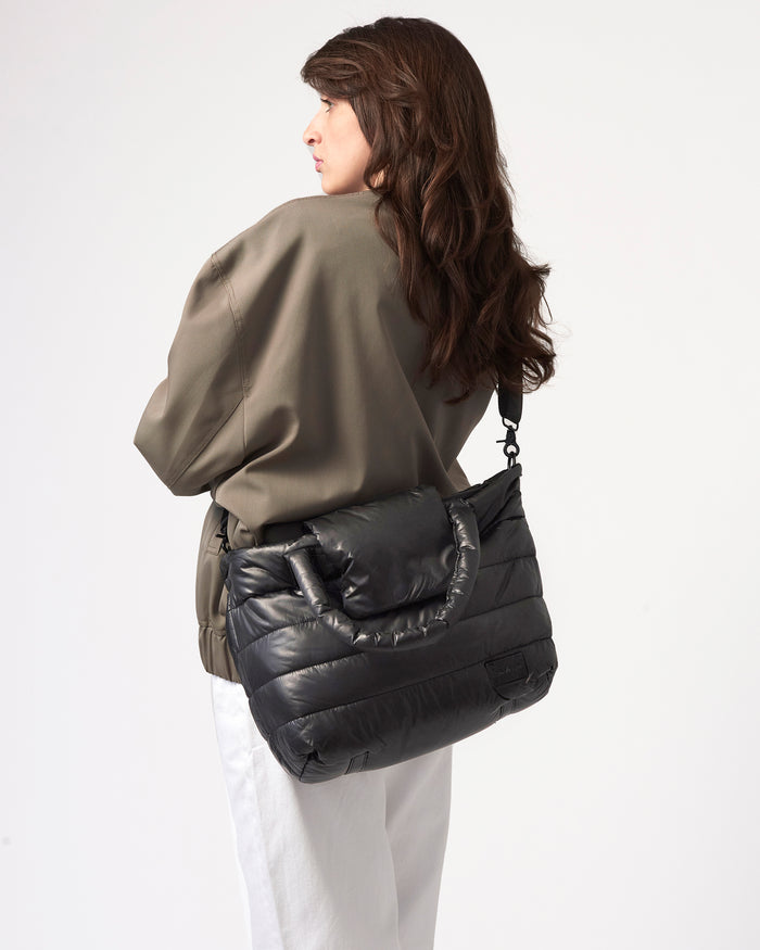 Woman carrying a black puffer bag on a white background