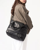 Person wearing a black quilted handbag on a white background