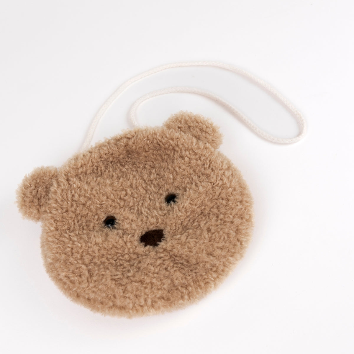 A small teddy bear face pouch made of soft, fuzzy brown fabric, featuring embroidered black eyes and nose, with a white strap, photographed on a clean white background.
