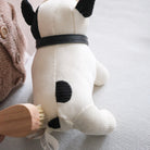 White dog toy with black spots held by a person wearing a brown sweater.