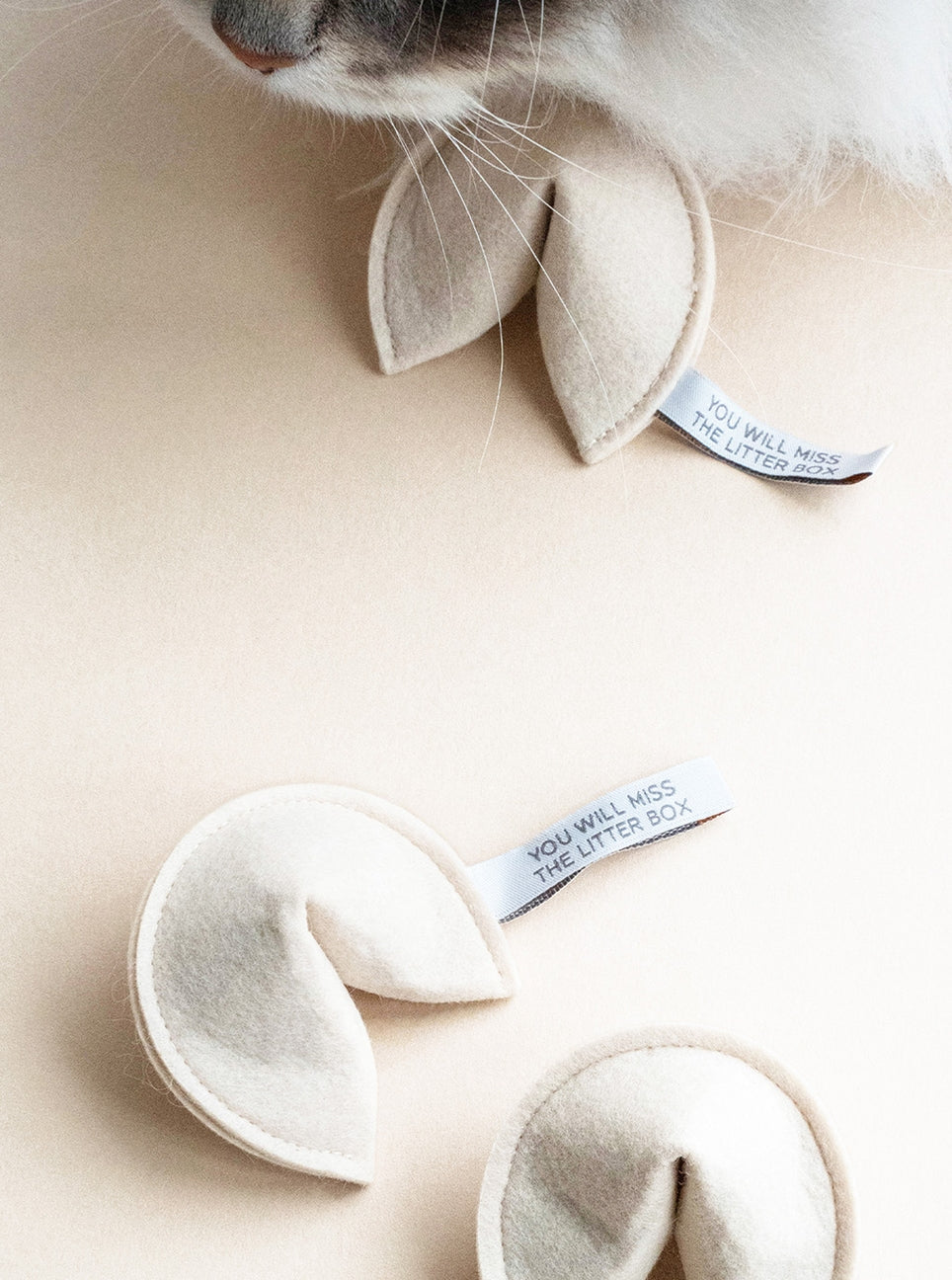 Catnip toys shaped like cat ears on a beige surface with a tag.