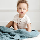 Child sitting on a bed with a blue blanket