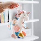 Plush toy with colorful hanging elements held by a hand against a blurred background