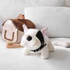 Plush toy bulldog on a light-colored surface with a bag and toothbrush in the background