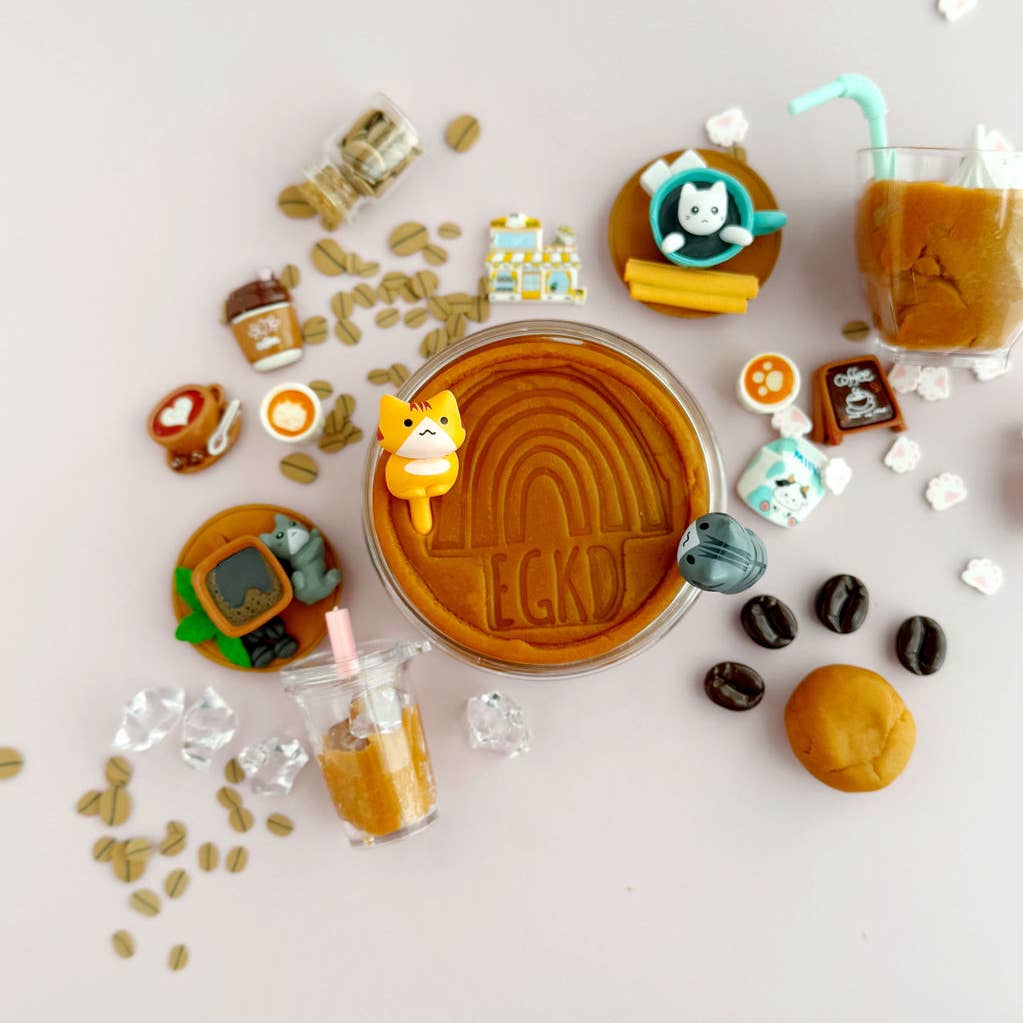 Cup of coffee with various coffee-themed cookies and decorations on a light pink background