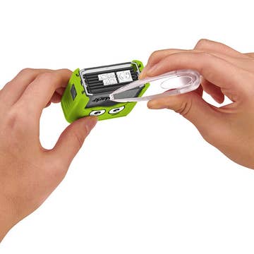 Green electronic device with a battery being removed by hands on a white background