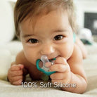 Baby lying on a blanket with a green and gray pacifier, text '100% Soft Silicone' below.