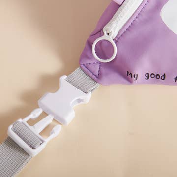 Close-up of a purple bag with a white strap and buckle on a beige background