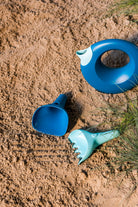 Blue and green plastic tools on a sandy surface