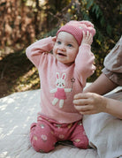 Baby in pink outfit with bunny design outdoors