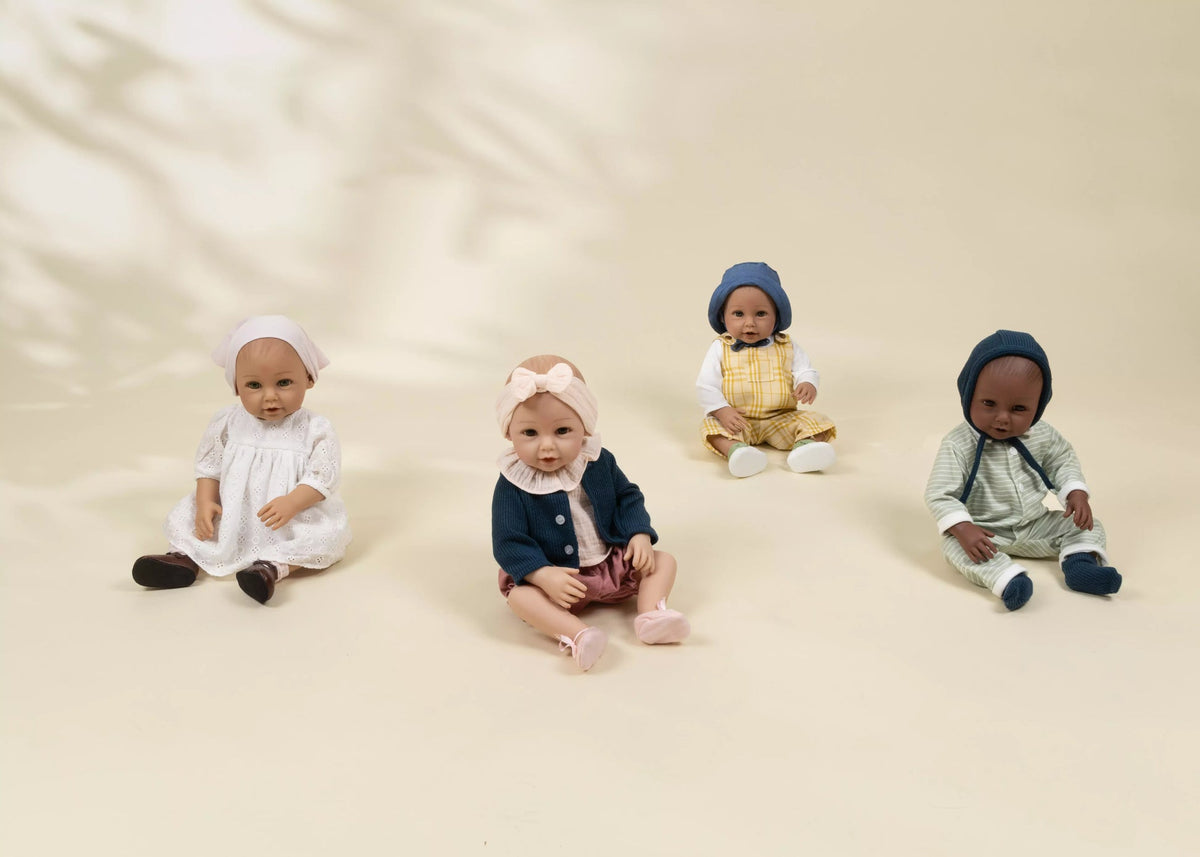 Four dolls in different outfits sitting on a beige background