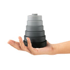 Stack of gray silicone coasters held in a hand on a white background
