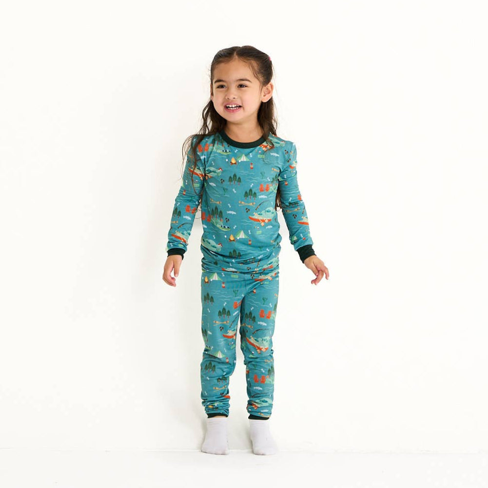 Child wearing teal pajamas with a forest and animal pattern on a white background