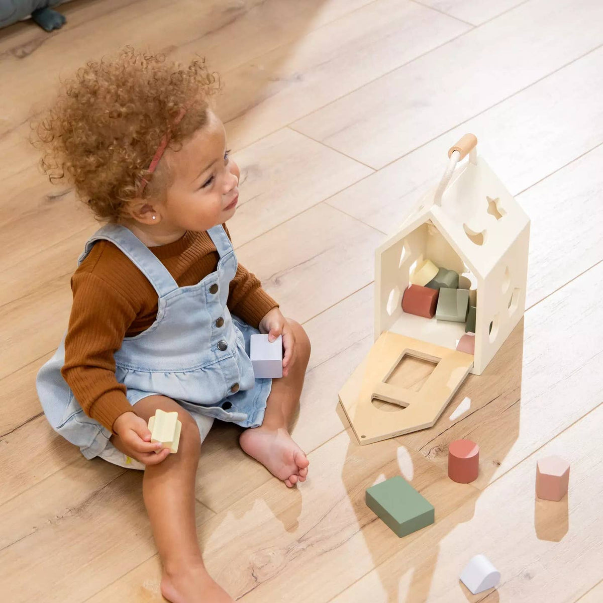 Child playing with wooden blocks on a wooden floor
