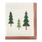 A folded knit blanket with an off-white center, featuring three stylized pine trees in dark green, light green, and brown, finished with a dusty rose pink ribbed border.