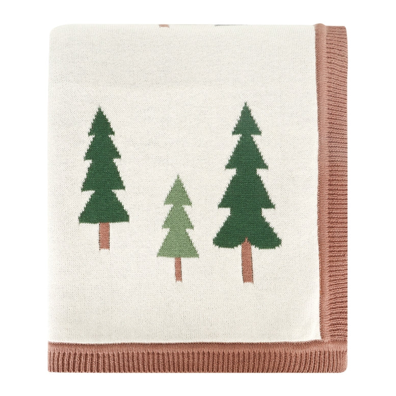 A folded knit blanket with an off-white center, featuring three stylized pine trees in dark green, light green, and brown, finished with a dusty rose pink ribbed border.