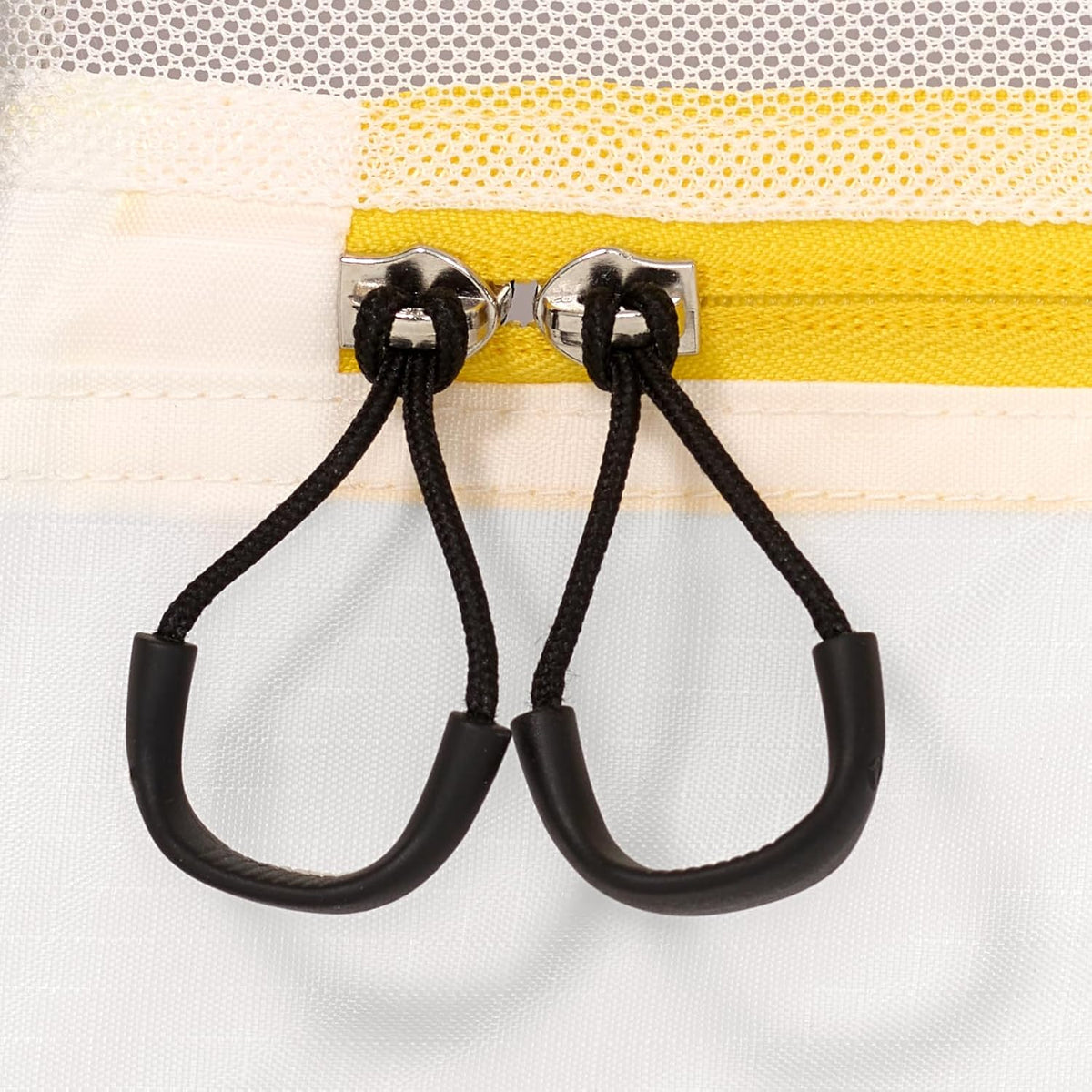 Close-up of a yellow bag with black straps and metal hooks on a white background