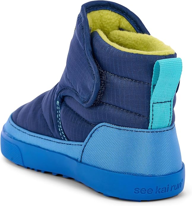 A high-top winter boot in navy blue with a bright blue sole, a turquoise pull tab, and a yellow-green fleece lining, shown from a rear three-quarter angle on a white background.