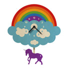 A whimsical wooden wall clock shaped like a rainbow cloud with a purple unicorn below. The clock face is light blue wood with cream-colored clouds and numbers, a purple center circle with the brand name 'papatas', and a large multicolor rainbow arching behind it.
