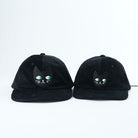 Two black caps with cat face designs on a white background