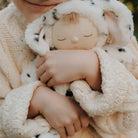 Child holding a soft toy wrapped in a knitted blanket