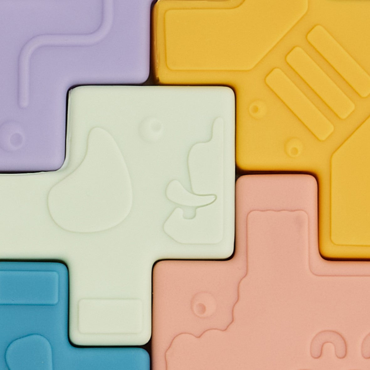 Colorful foam puzzle tiles with embossed designs on a multicolored background