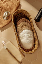 Wicker basket with cotton pads on a beige tiled surface