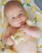 Baby holding a teething toy on a lemon-patterned blanket