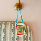 Small embroidered bag with a cactus design hanging from a wall hook.