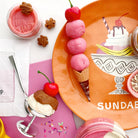 Ice cream-themed table setting with pink ice cream, waffles, and a 'Sundae' plate.