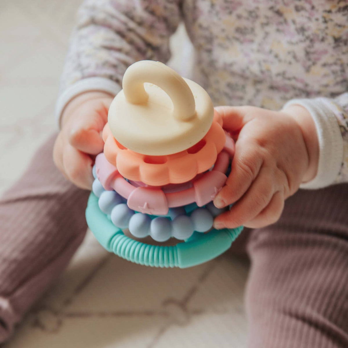 Child holding a colorful stacking toy with soft focus background