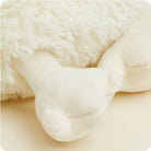 A close-up of a fluffy white Warmies chicken plush toy, focusing on its wing and textured plush fabric against a neutral background.