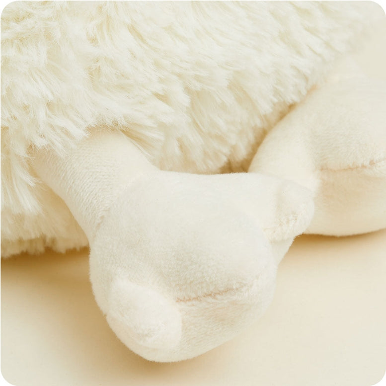A close-up of a fluffy white Warmies chicken plush toy, focusing on its wing and textured plush fabric against a neutral background.